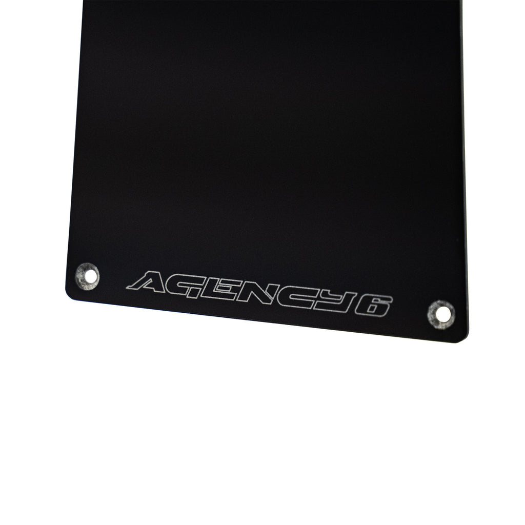 Black metal plate with 'Agency 6' engraving on a white background