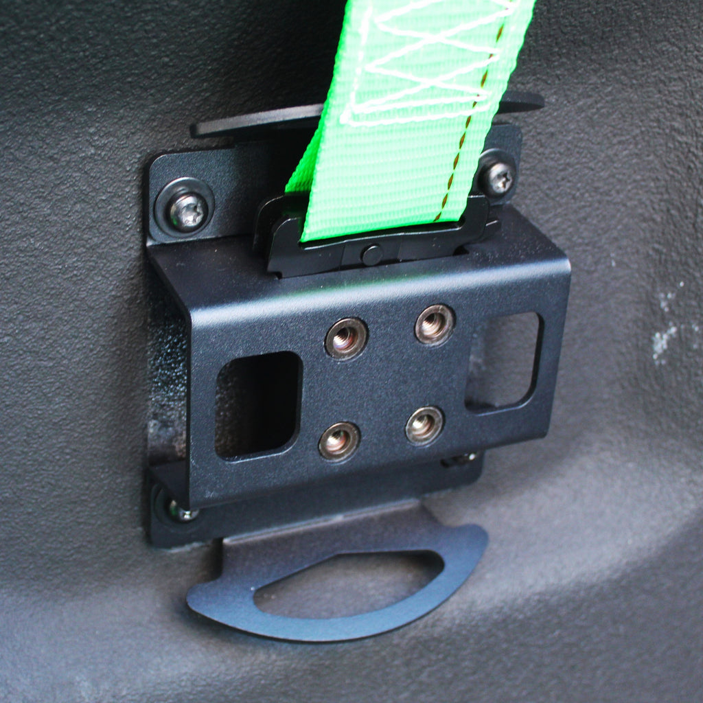 Black metal strap holder with green webbing on a textured gray surface