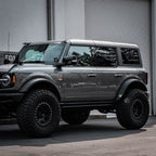 Gray SUV with large tires parked in front of a building