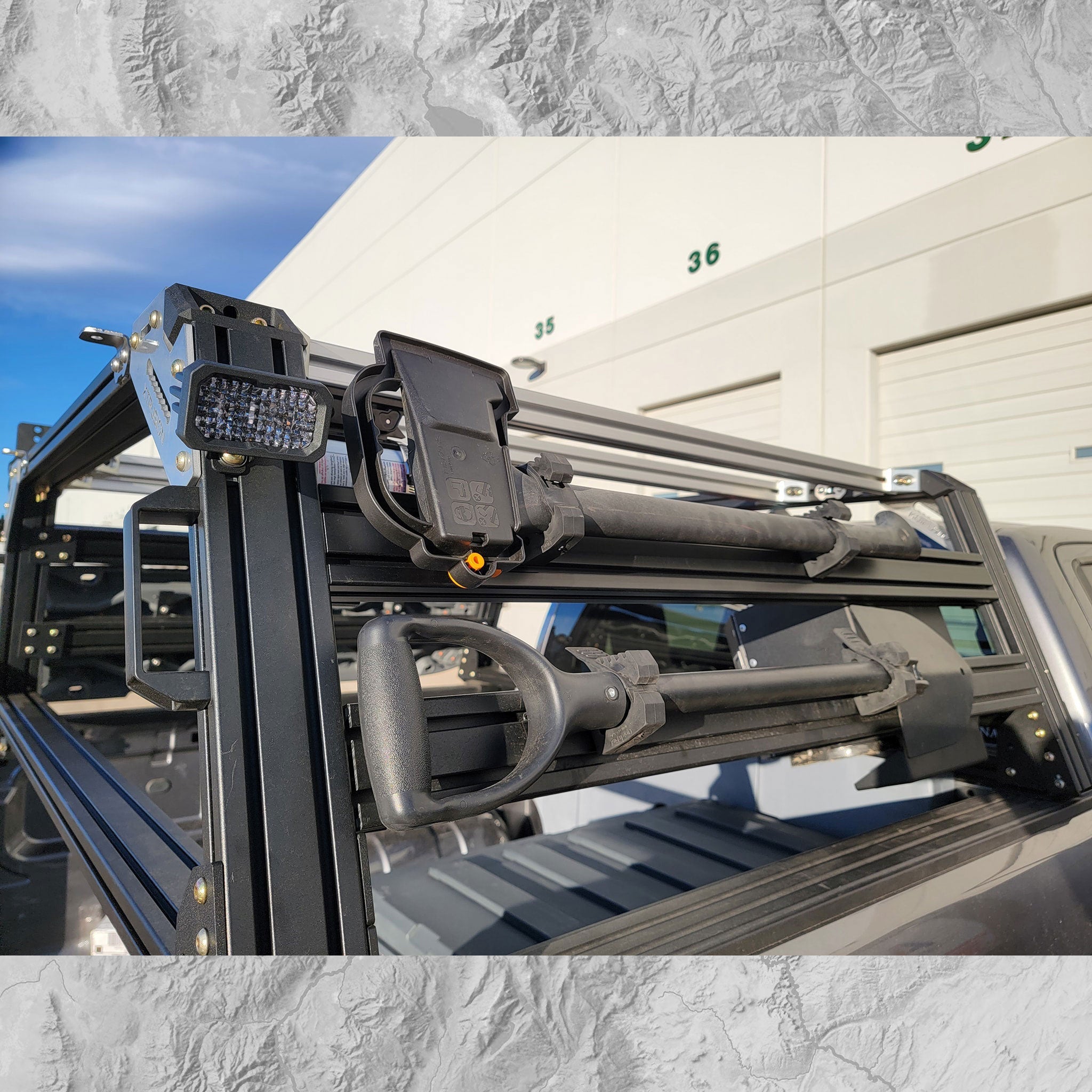 Close-up of a truck bed rack with a building and blue sky in the background