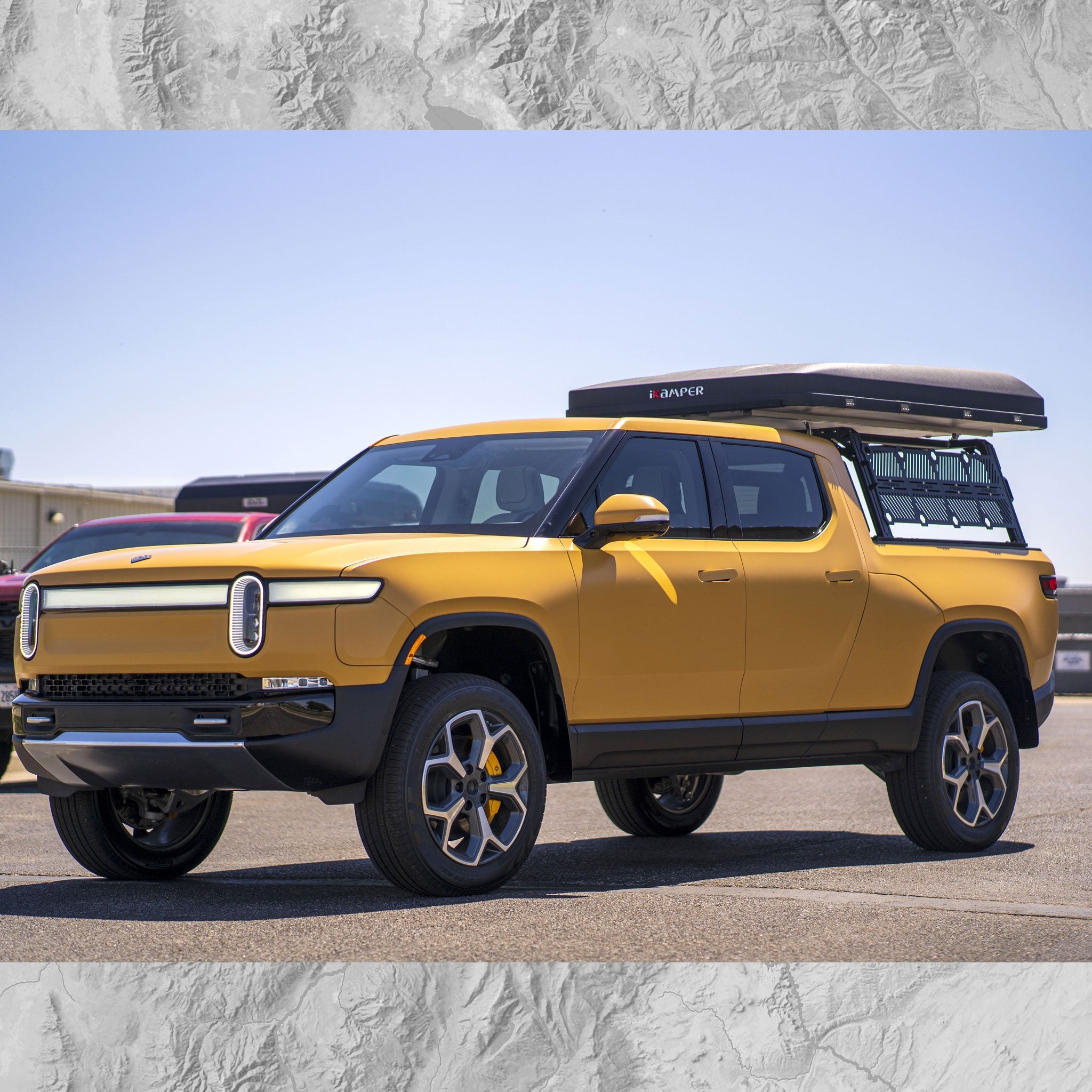 Yellow electric pickup truck with a camper shell on a clear day.